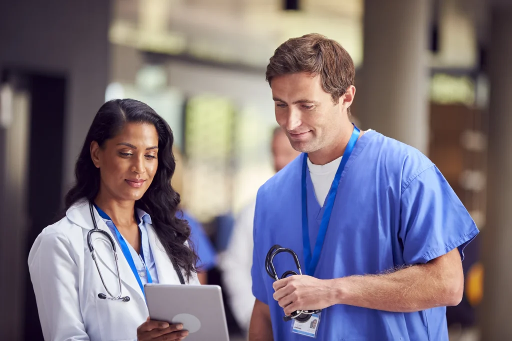 Two medical staff in white coats and scrubs